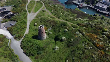 Amlwch-port-red-brick-disused-abandoned-windmill-aerial-view-North-Anglesey-Wales-rising-top-down-shot