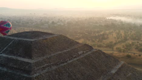 Aerial-view-of-hot-air-baloon-flying-by-the-pyramid-of-the-Aztec-culture-in-Teotihucan-Mexico-during-sunrise,-4K
