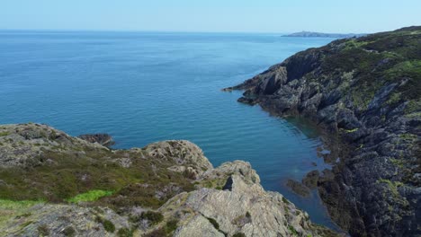 Peaceful-Amlwch-Anglesey-North-Wales-rugged-mountain-coastal-walk-aerial-view-right-orbit-above-rocky-coast