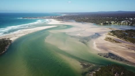 Aerial-footage-of-the-mouth-of-the-Wallagaraugh-River-at-low-tide-with-Mallacoota-in-the-background,-Victoria,-Australia,-December-2020