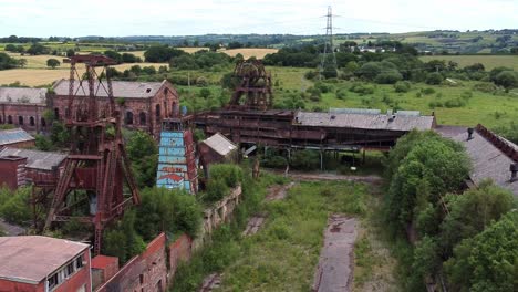 Abandoned-old-overgrown-coal-mine-industrial-museum-buildings-aerial-view-slow-rise-right