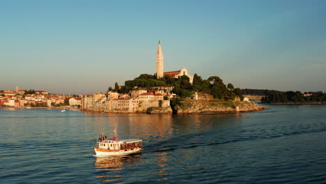 Cruising-Fishing-Boat-Crossing-On-The-Seafront-Old-City-Of-Rovinj-In-Istria,-Croatia-At-Sunset