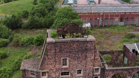 Abandoned-old-overgrown-coal-mine-industrial-rusting-pit-wheel-aerial-view-orbit-left-close