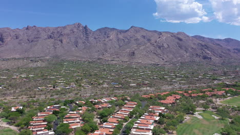 Aerial-forward-over-real-estate-subdivision-at-Catalina-Foothills,-rocky-mountains-in-background,-Tucson