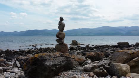 Balanced-spirituality-meditation-pebbles-piled-on-alien-rocky-mountain-range-beach-coastline-push-in-right