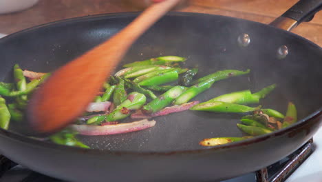 Stir-frying-asparagus-and-onions-in-a-pan-on-the-stove-with-a-wooden-spoon