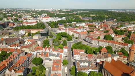 Aerial-flyover-beautiful-old-town-of-Gdansk-with-famous-church,historic-buildings-and-green-trees-in-summer