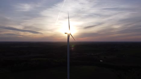 Aerial-of-wind-turbine-silhouette-over-farmland-fields-during-sunset