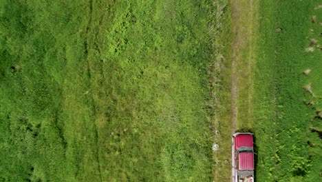 Bird's-Eye-View-Of-A-Red-Farm-Truck-Driving-On-A-Rough-Road