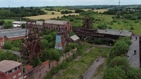 Abandoned-old-overgrown-coal-mine-industrial-museum-buildings-aerial-view-zoom-in-slow