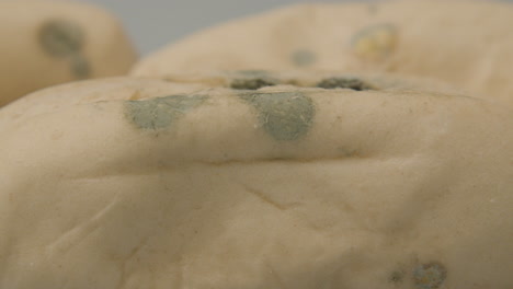 extreme-close-of-Fungal-mold-spots-on-several-pistolet-breads-against-a-white-background