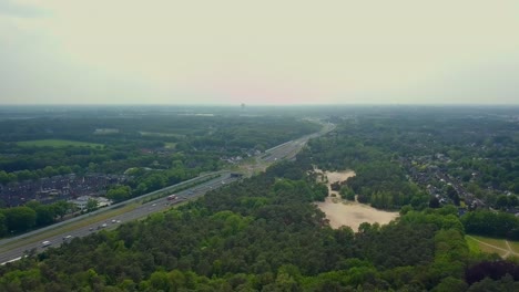 Aerial-drone-view-of-the-highway,-forest,-and-suburban-in-the-Netherlands