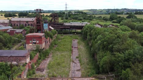 Abandoned-old-overgrown-coal-mine-industrial-museum-buildings-aerial-view-fly-past