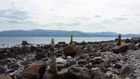Balanced-spirituality-meditation-pebbles-piled-on-alien-rocky-mountain-range-beach-coastline-dolly-left