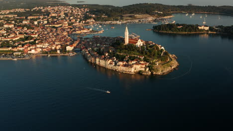 Aerial-Panoramic-View-Of-Coastal-Town-In-Rovinj-With-Boat-Sailing-On-The-Adriatic-Sea-In-Istria,-Croatia