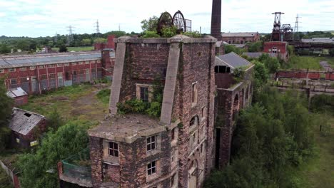 Abandoned-old-overgrown-coal-mine-industrial-rusting-pit-wheel-ruin-aerial-view-rising