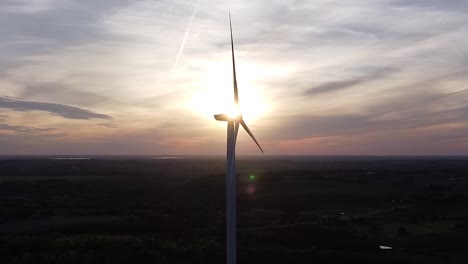 Aerial-of-wind-turbine-silhouette-over-farmland-fields-during-sunset