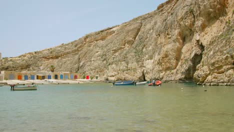 Beautiful-view-of-the-Inland-Sea-with-small-fishermen's-huts,-rocky-cliffs-and-sea-cave-on-the-island-of-Gozo-in-Malta-on-a-sunny-summer-day
