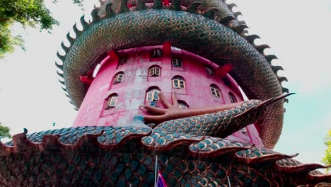 Looking-up-at-the-Wat-Samphran-Temple-with-a-dragon-coiled-around-the-outside-of-the-red-temple-in-Amhoe-Sam-Phran-Province-Thailand