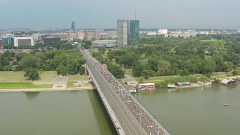 Toma-Aérea-De-Miles-De-Corredores-En-Un-Maratón-Cruzando-Un-Puente-En-Belgrado