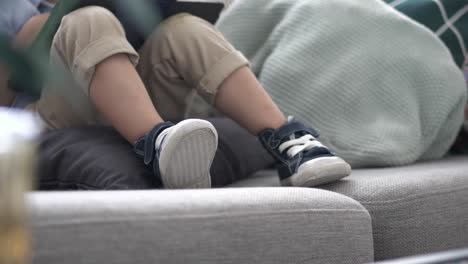 Kleinkind-Trägt-Freizeitschuhe,-Während-Es-Auf-Der-Couch-Sitzt