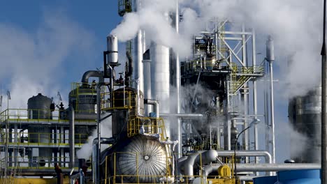 Stahlrohr--Und-Tankinstallation-Der-Großen-Chemiefabrik-Mit-Qualmenden-Schornsteinen,-Die-Die-Luft-Verschmutzen