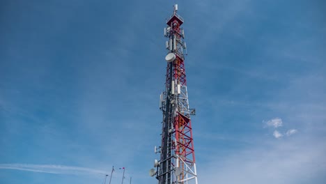 Timelapse-of-a-telecommunication-tower-with-5G-antennas-covered-by-fast-moving-fog-clouds-against-the-blue-sky