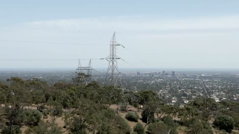 Transmission-Tower-In-Dense-Trees-With-City-Landscape-Of-Adelaide-At-Backdrop-In-Australia