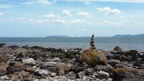 Balanced-spirituality-meditation-pebbles-piled-on-alien-rocky-mountain-range-beach-coastline-right-parallax