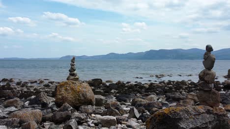 Balanced-spirituality-meditation-pebbles-piled-on-alien-rocky-mountain-range-beach-coastline-close-left-orbit