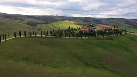 aerial-view-of-amazing-landscape-scenery-of-Tuscany-in-Italy---farmhouse,hills-fields,-vineyards,-cypress-trees-along-white-road