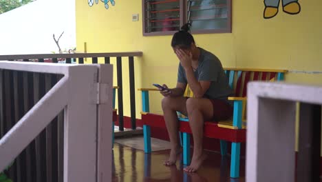Lonely-And-Sad-Filipina-Orphan-Girl-Looking-Into-The-Picture-Of-Her-Mother-On-Her-Phone-At-The-Orphanage-Home-In-The-Philippines---medium-shot