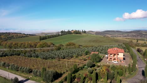 Beautiful-landscape-scenery-of-Tuscany-in-Italy---farmhouse,-cypress-trees-along-white-road---aerial-drone-view