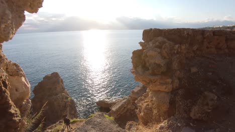 Walk-through-shot-capturing-rocky-cliffs-and-sun-kissed-sea-in-Antalya-Turkey