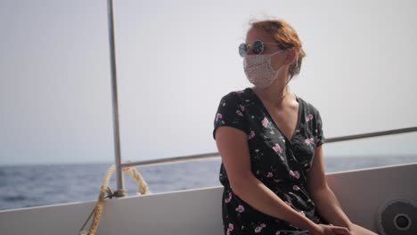 Attractive-woman-wearing-face-mask-and-sunglasses-while-on-a-boat-ride-during-summer-in-slow-motion