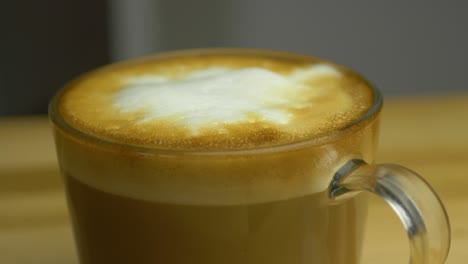 Slow-shallow-focus-slide-shot-of-Cup-of-hot-Cappuccino-on-wooden-table
