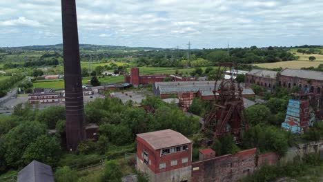 Abandoned-old-overgrown-coal-mine-industrial-museum-colliery-buildings-aerial-view-dolly-left