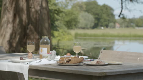 Delicious-breakfast-set-up-on-table-in-the-countryside-near-pond---medium