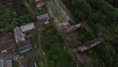 Abandoned-old-overgrown-coal-mine-industrial-museum-buildings-aerial-top-down-reveal-view