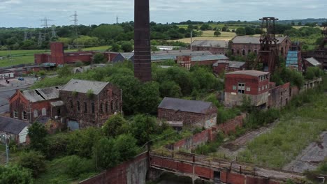 Abandoned-old-overgrown-coal-mine-industrial-museum-neglected-buildings-aerial-view-low-orbit-right