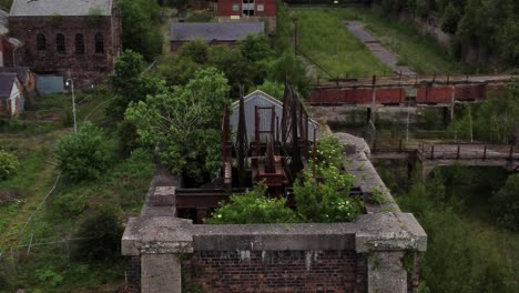 Abandoned-overgrown-landmark-rusting-coal-mine-industrial-museum-buildings-aerial-view-orbit-right