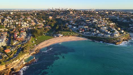 Aerial-View-Of-Bronte-Beach,-Park-And-Coastal-Suburb-City-Of-Bronte---Bronte-Baths-With-Clear-Blue-Water-At-Sunset-In-NSW,-Australia