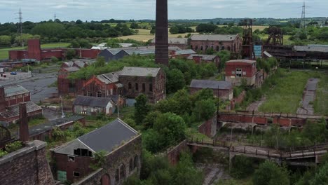 Abandoned-old-overgrown-coal-mine-industrial-museum-buildings-aerial-view-forward-moving