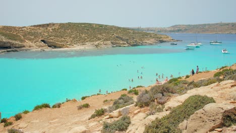 Blue-Lagoon,-Comino,-Malta-–-Aerial-shot-of-a-busy-blue-lagoon-filled-with-ships
