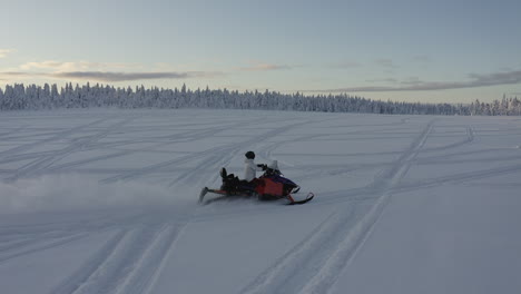 Aerial-drone-shot-following-a-snowmobiler-with-speed-in-deep-snow-in-the-cold-winter-landscape-of-Sweden