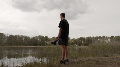 Young-man-standing-in-nature-holding-gimbal-with-camera-for-filmmaking