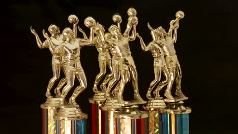 Series-of-volleyball-trophies-for-the-champions,-rotating-on-a-black-background
