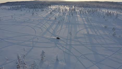 Top-view-drone-aerial-shot-of-a-snowmobile-ride-on-snowy-track-through-cold-winter-forest-in-Sweden