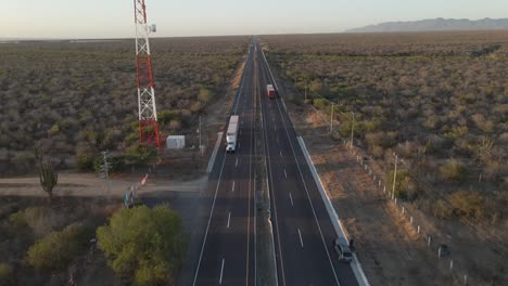 Trucks-driving-in-opposite-directions-on-empty-desert-highway,-aerial-view