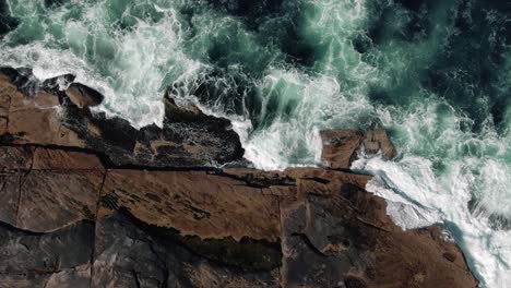Top-View-Of-Sea-Waves-Crashing-On-Rocky-Coast-In-Summer